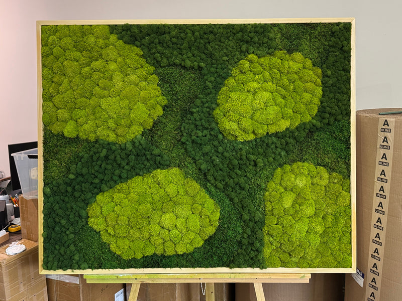 Moss wall art on an easel with cardboard boxes in the background